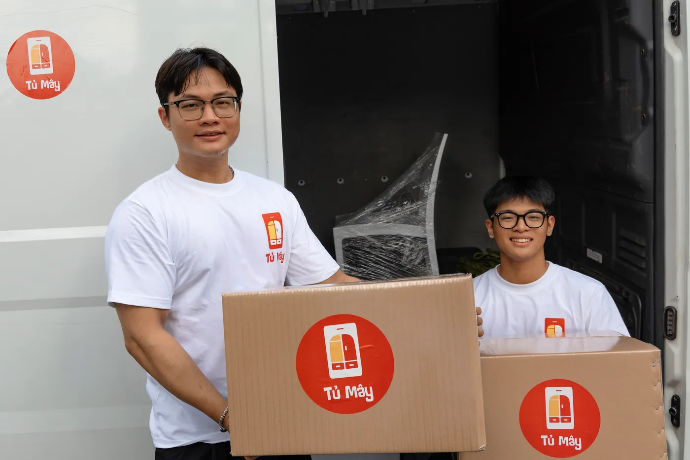 A crew member carrying a Tủ Mây box out to the van