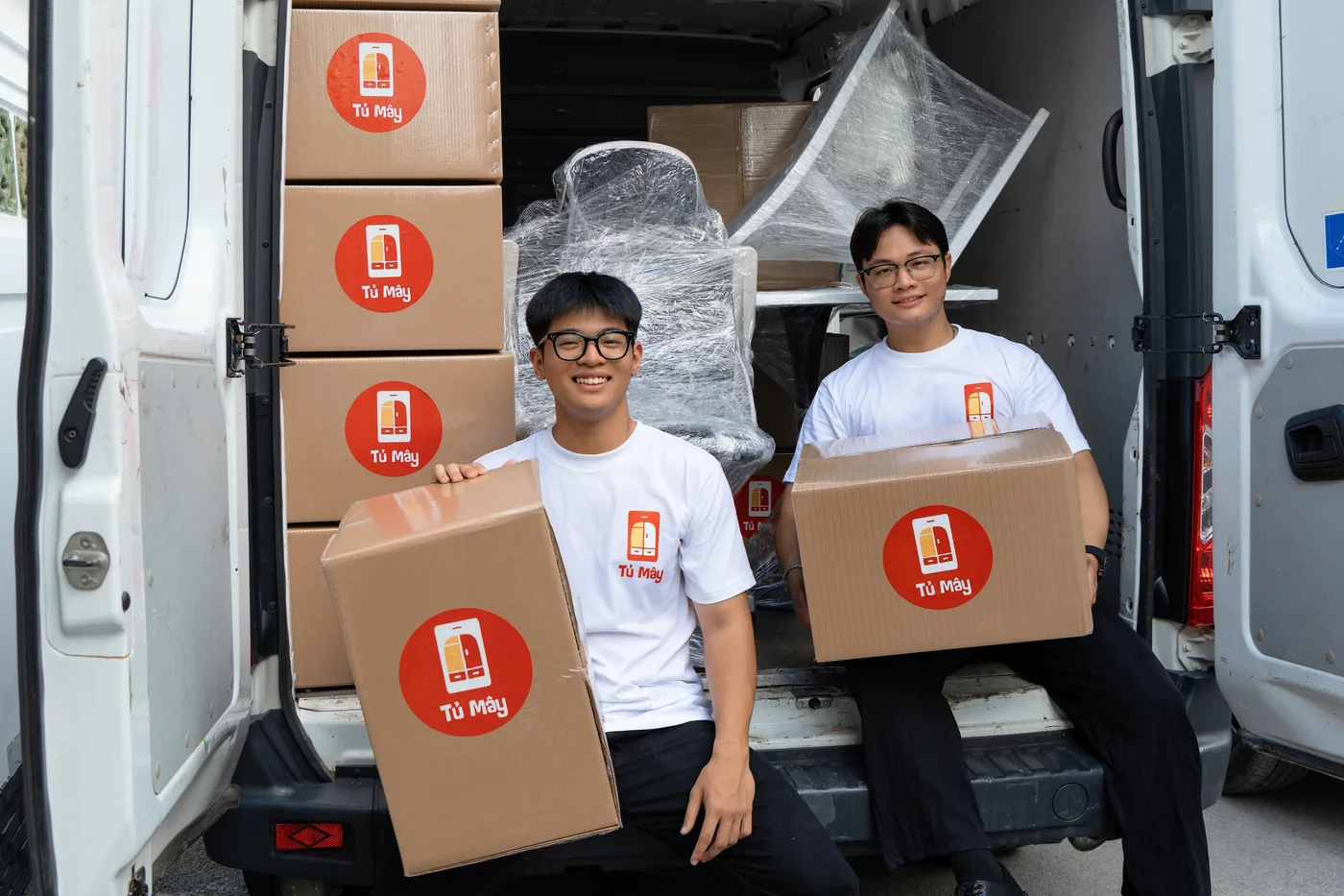 Two crew members with boxes at the van door
