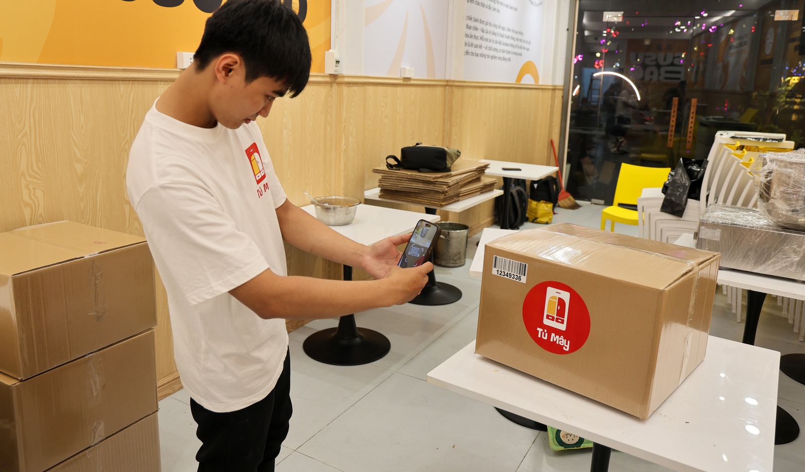 A Tủ Mây crew member scanning the barcode on a sealed box with a phone