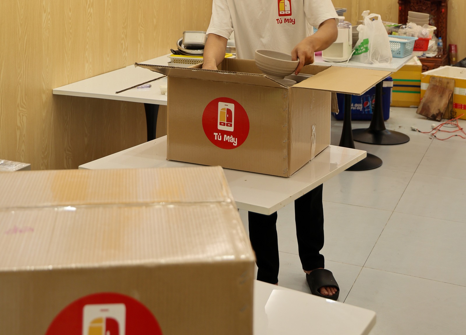 A crew member packing tableware into a Tủ Mây box