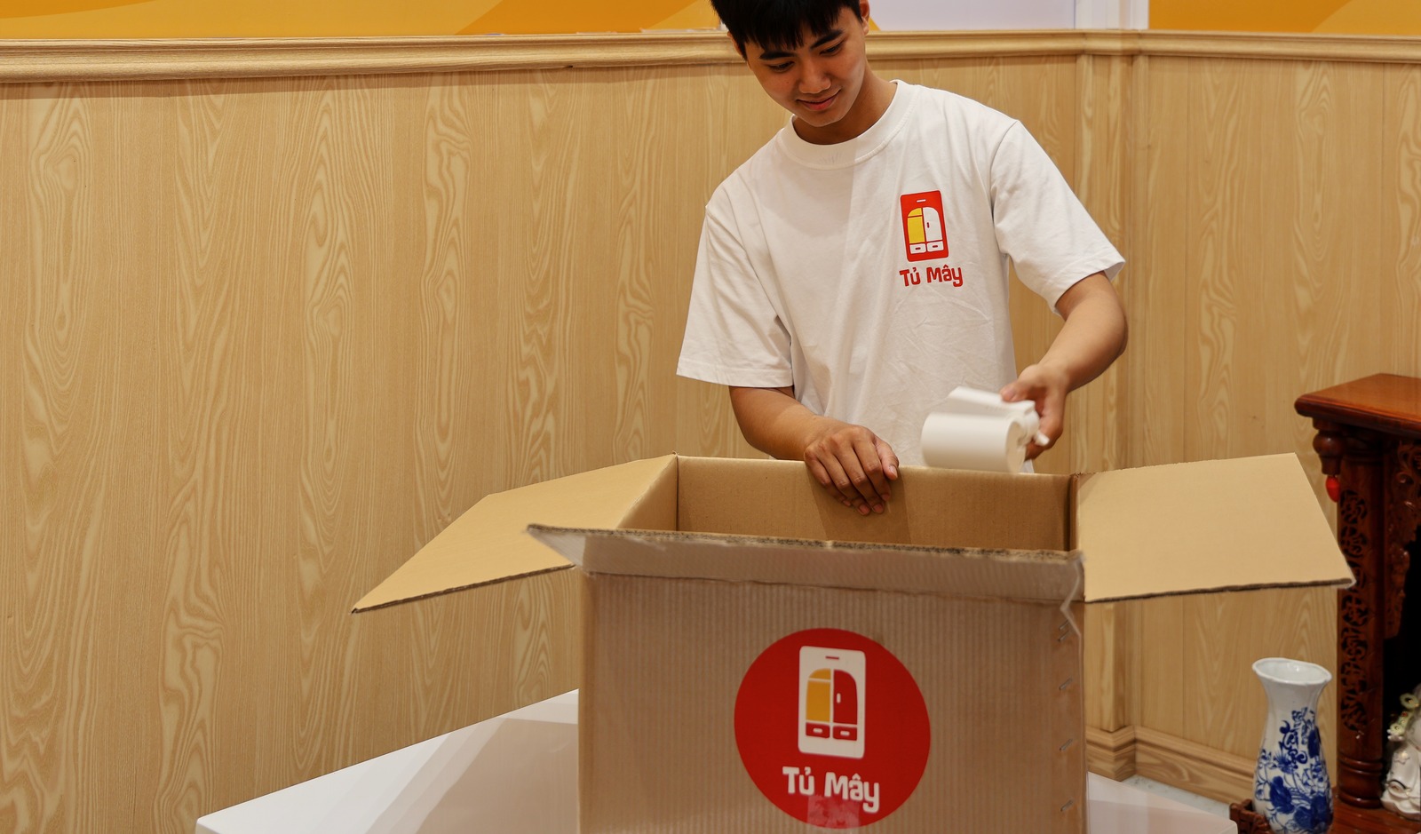 A crew member packing tableware into a Tủ Mây box inside the restaurant