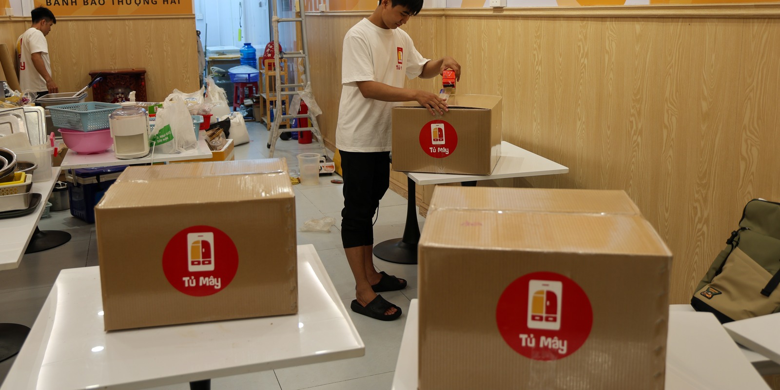 Sealed boxes on the tables, another crew member packing behind