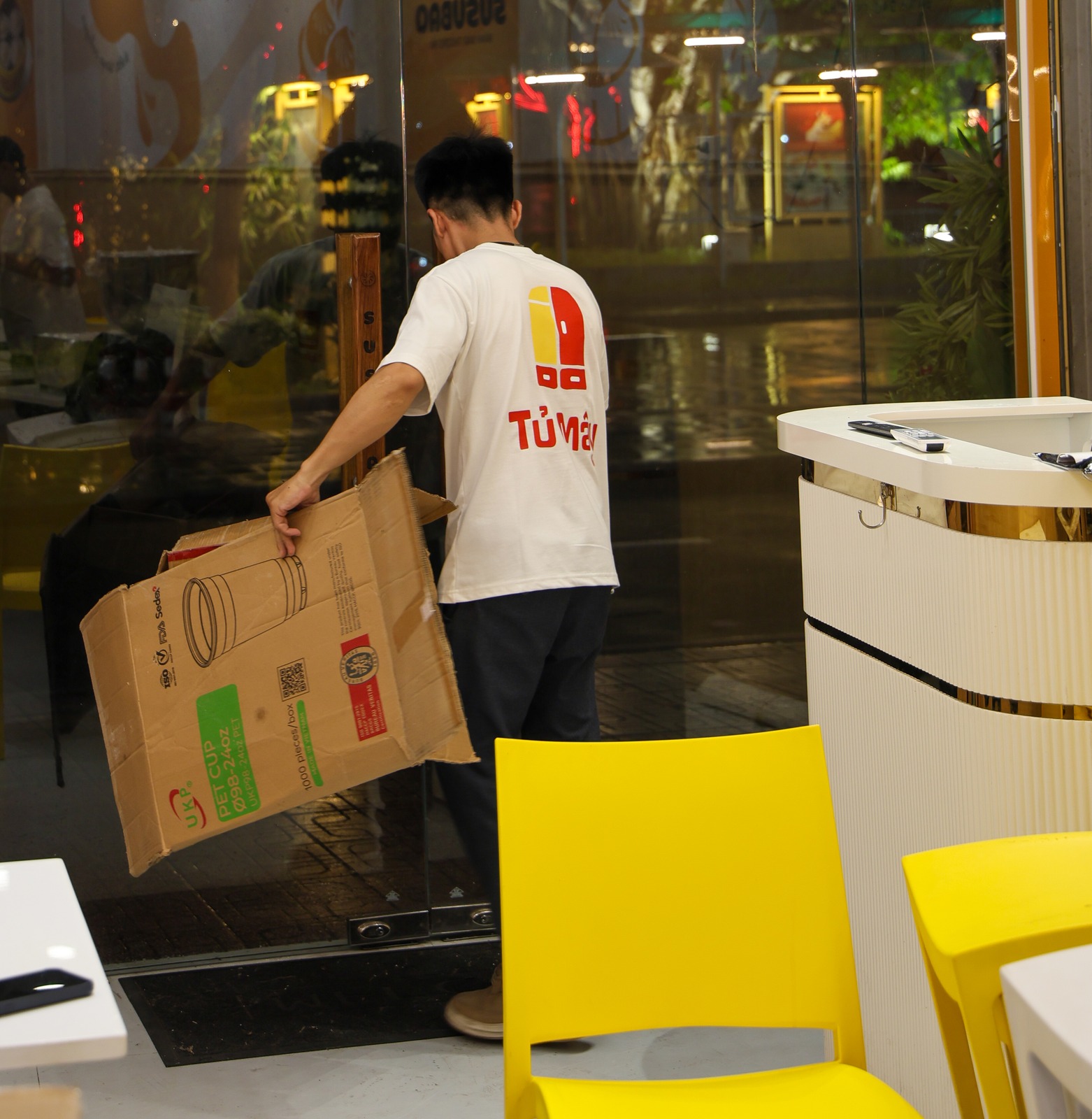A crew member carrying a large box towards the shopfront