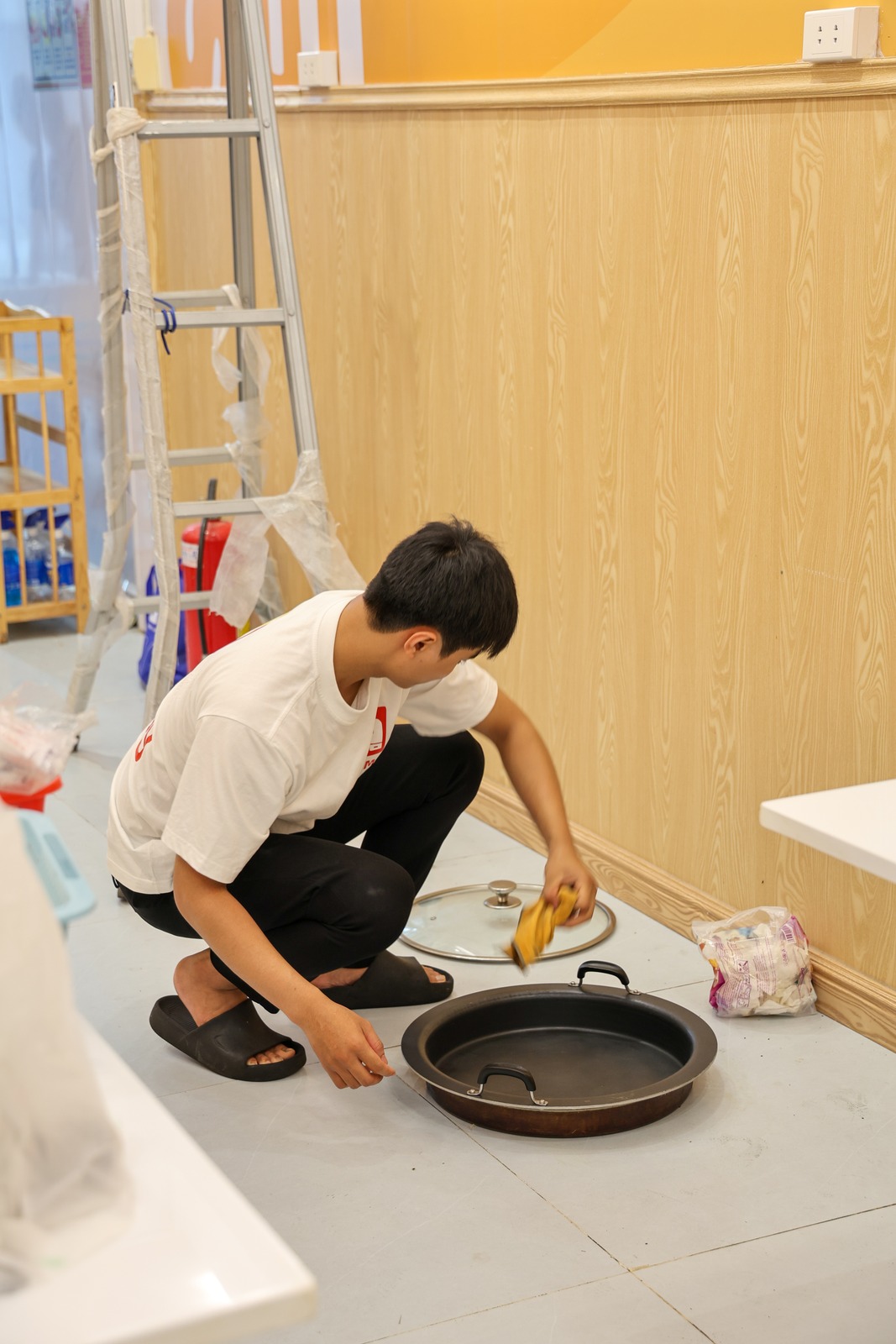 A crew member cleaning a pan and its glass lid before it is packed
