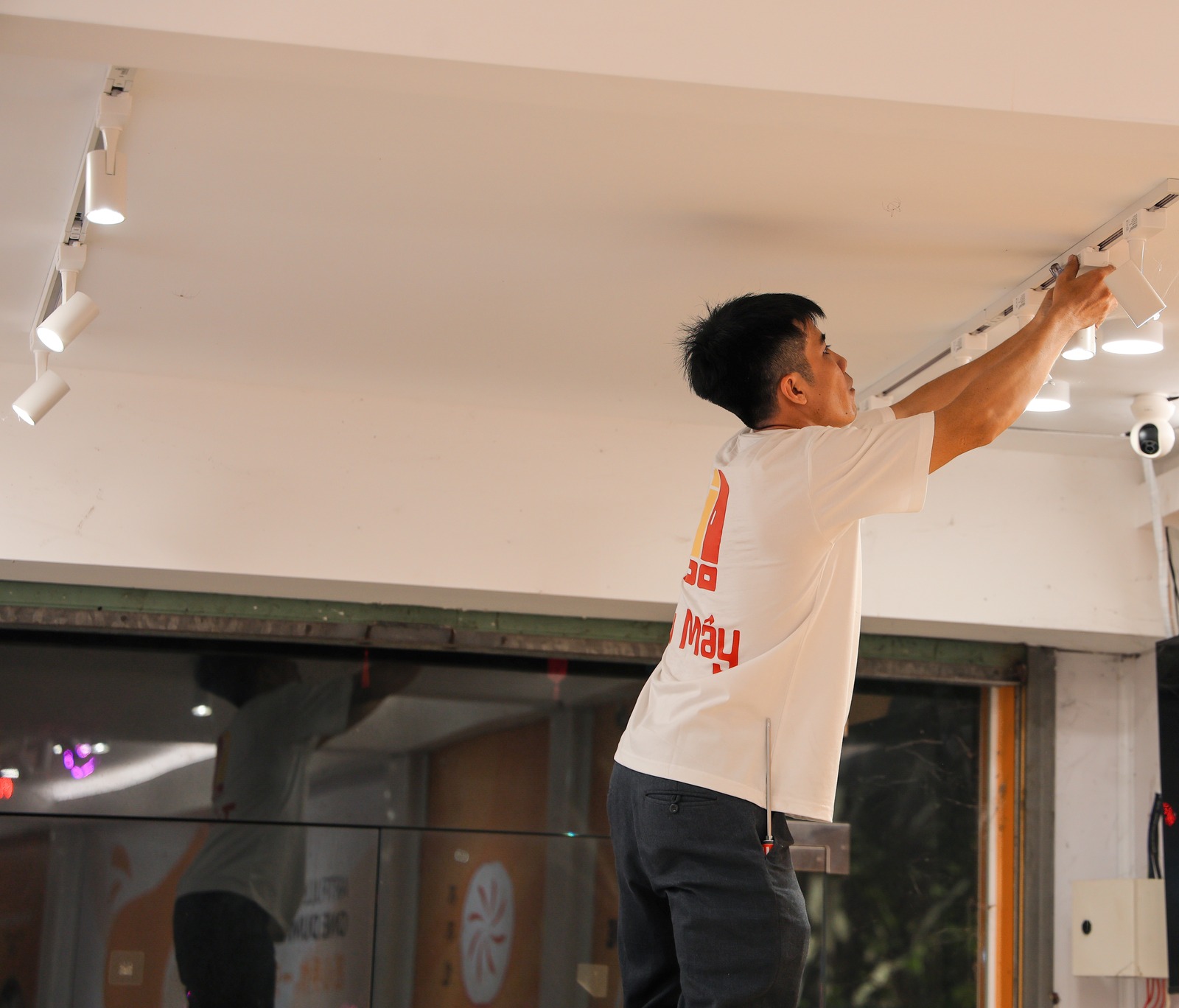 A crew member taking a long light bar down from the ceiling