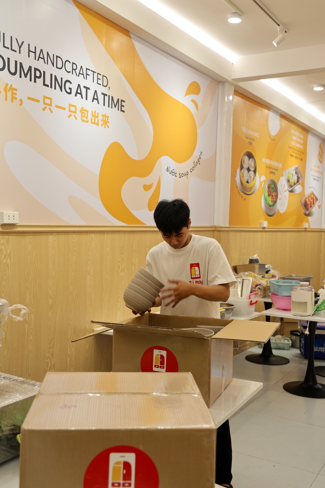 A crew member stacking bowls into a box, a sealed box in the foreground